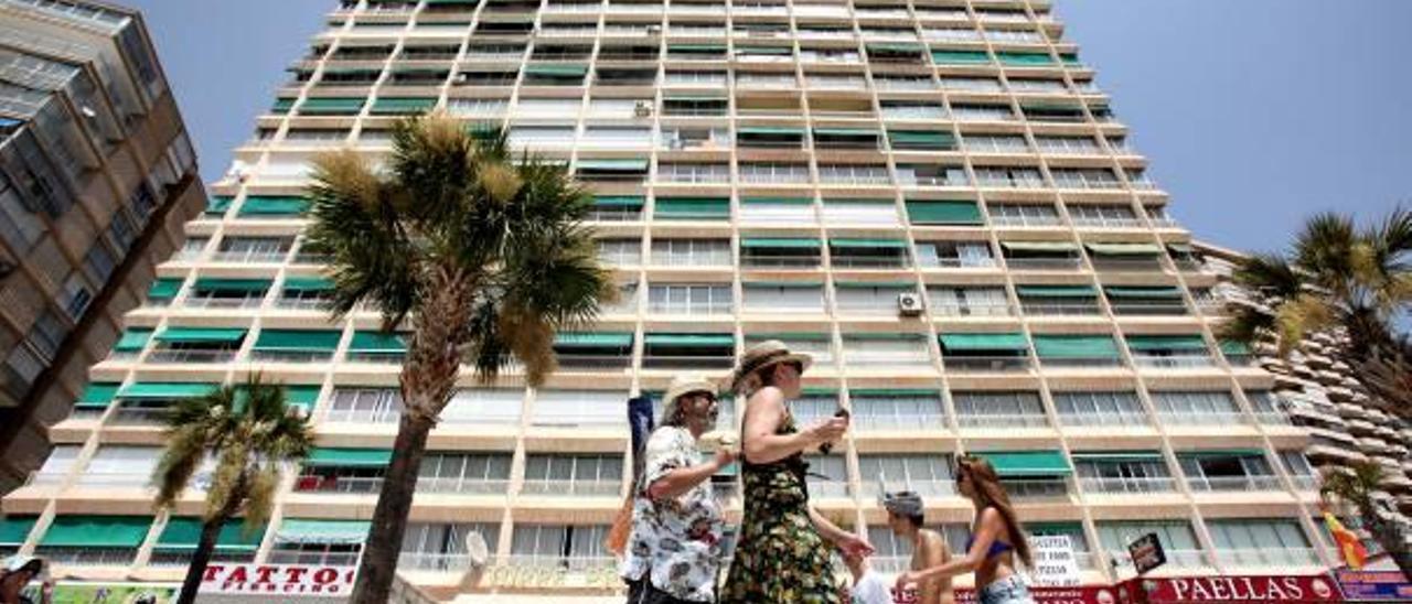 Turistas pasan junto a un edificio de apartamentos en Benidorm este verano.