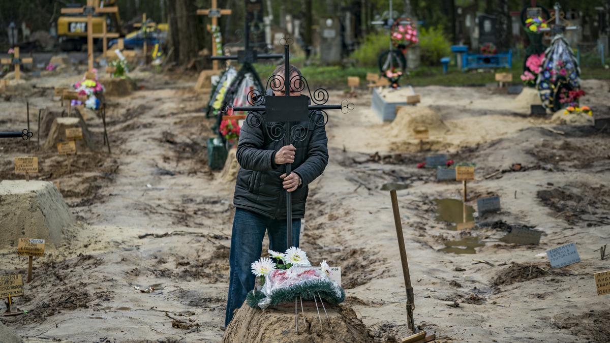 Un hombre sujeta una cruz, tras el entierro de un familiar muerto durante la guerra en Ucrania, en la ciudad de Chernihiv