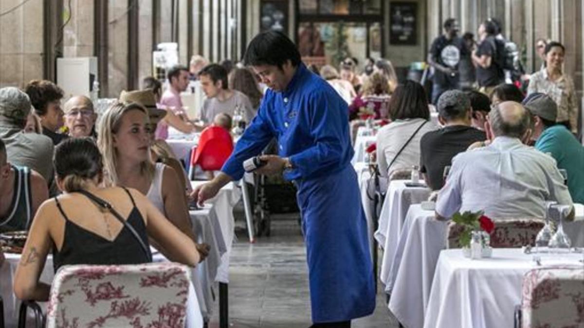 Un camarero sirve en una terraza de la plaza Reial de Barcelona, ayer.