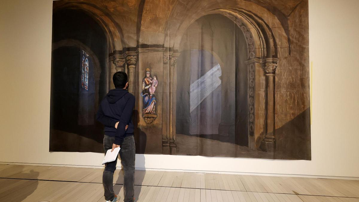 Un espectador observa la reproducción de uno de los telones de Castelao en la que exposición del centenario de la Polifónica.