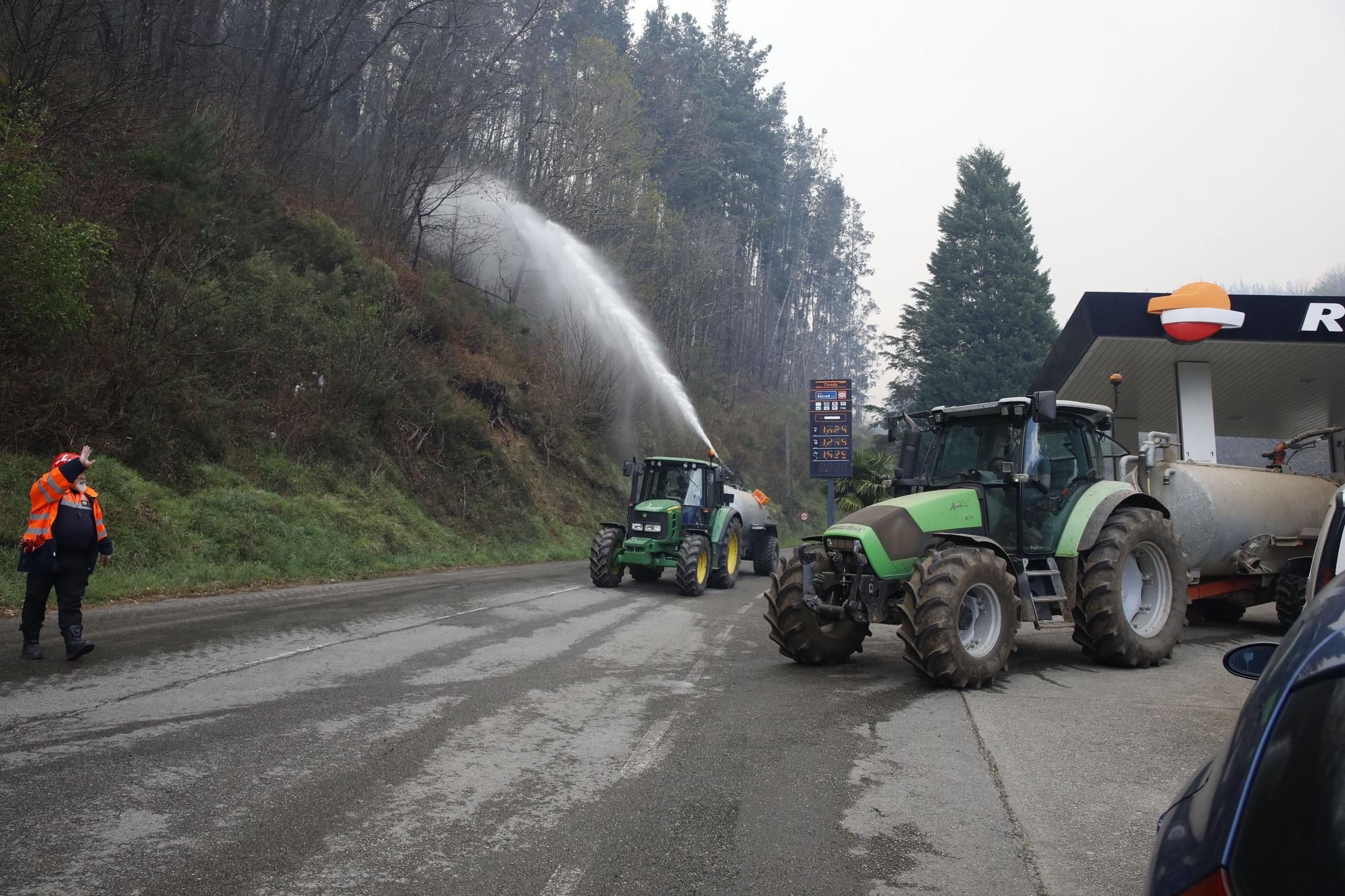 Agricultores ayudando en la extinción de los focos de fuego y enfriando las inmediaciones de la gasolinera de Navelgas