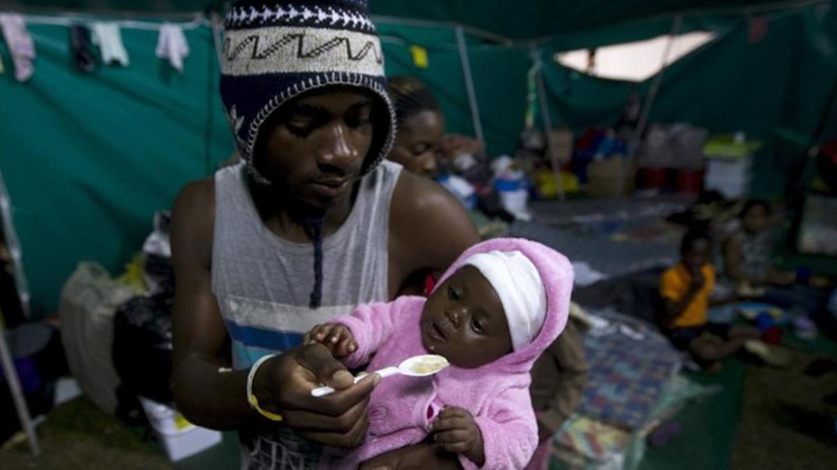 Un extranjero alimenta a su bebé en una tienda donde han sido realojados en Isibingo, en el sur de Durban, este lunes.