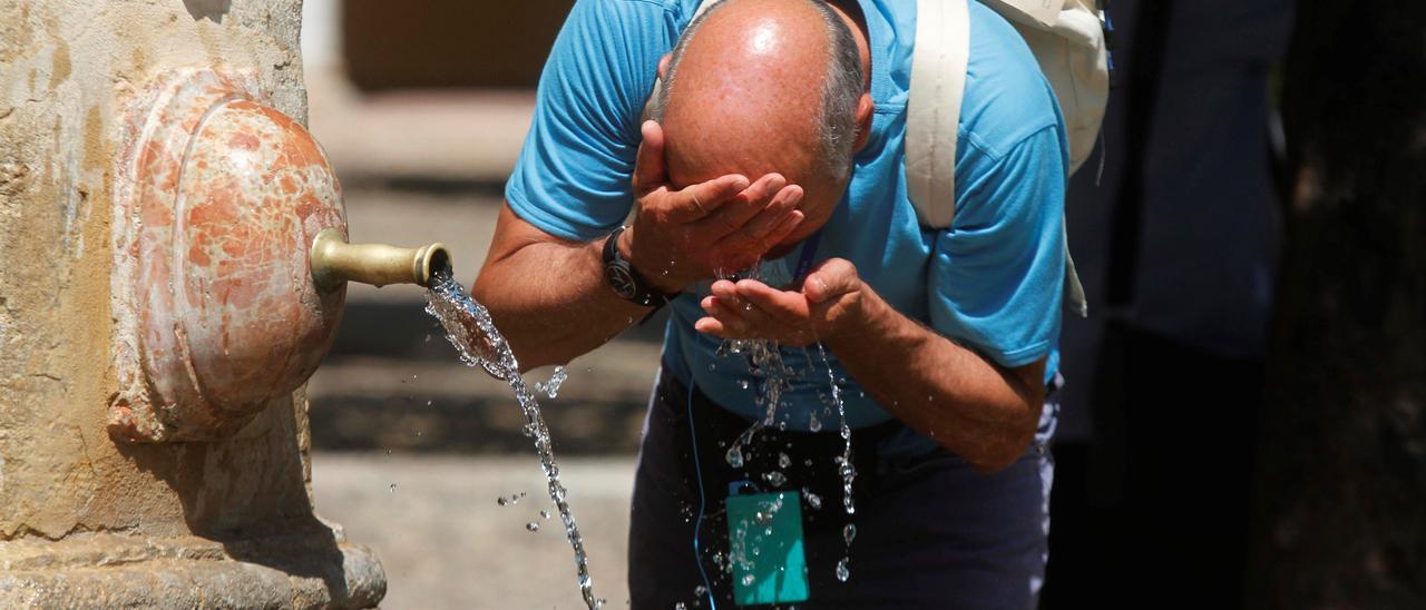 Un hombre se refresca la cabeza en el Patio de los Naranjos.