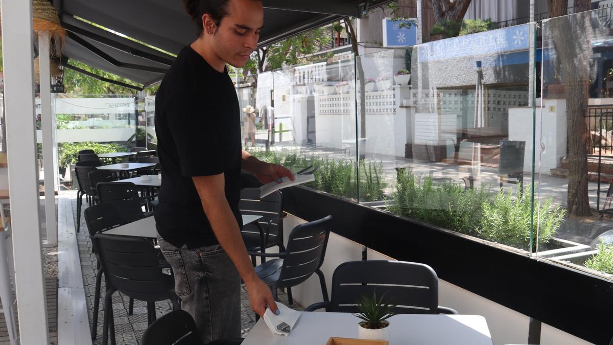 Un cambrer prepara una taula en una terrassa