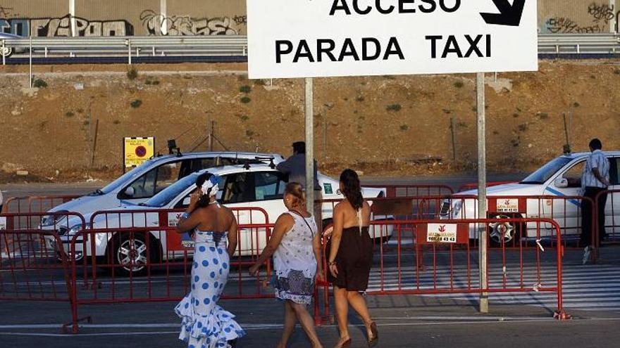 Unos taxistas esperan en la parada del Real de la Feria de Málaga a que lleguen clientes.