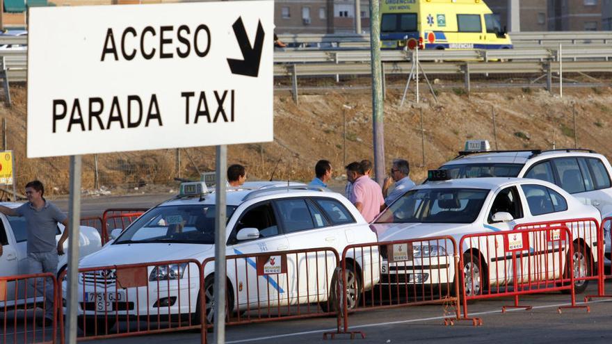 Varios taxistas esperan a que lleguen clientes en la parada de taxis durante la Feria en el Real Cortijo de Torres.