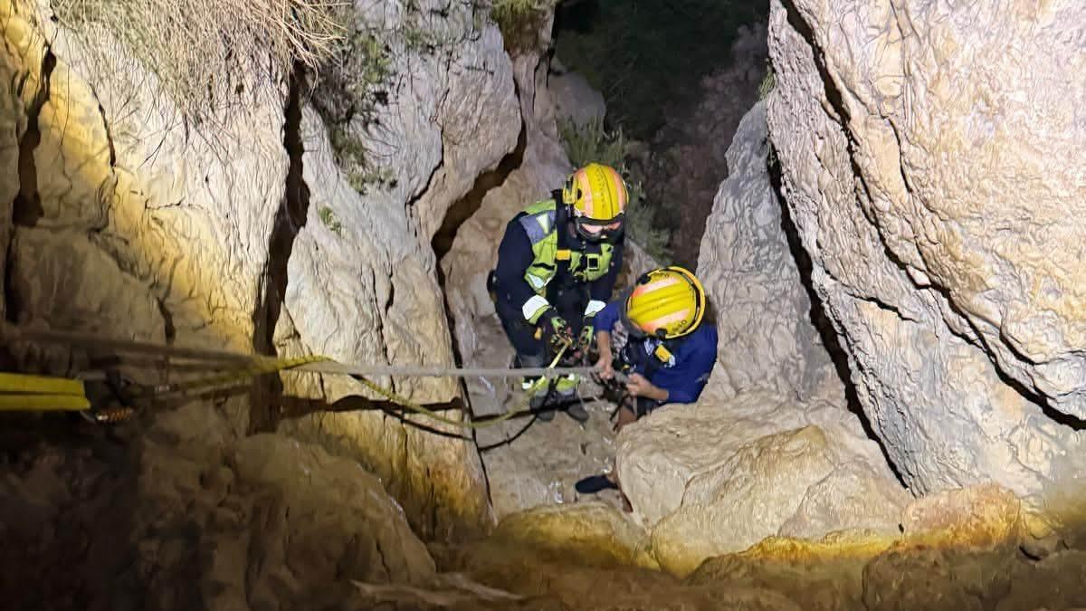 Un bomber ajuda un menor a escalar per una de les parets del barranc de la cala de Testos