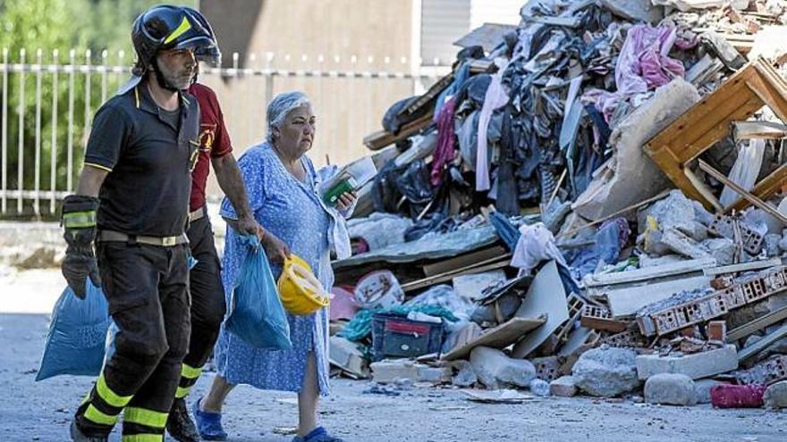 Bombers italians ajudant una dona durant l&#039;evacuació d&#039;Amatrice