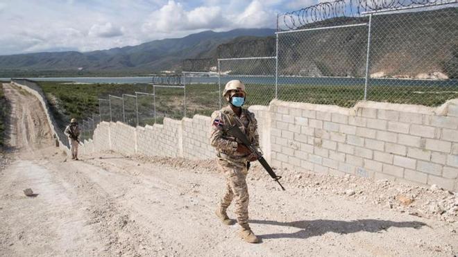 Soldados dominicanos patrullan junto a uno de los tramos de la valla fronteriza que separa al país de su vecino Haití.