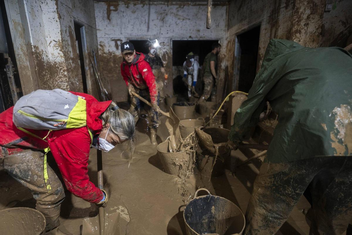 Voluntarios retiran lodo de un edificio afectado por la dana.