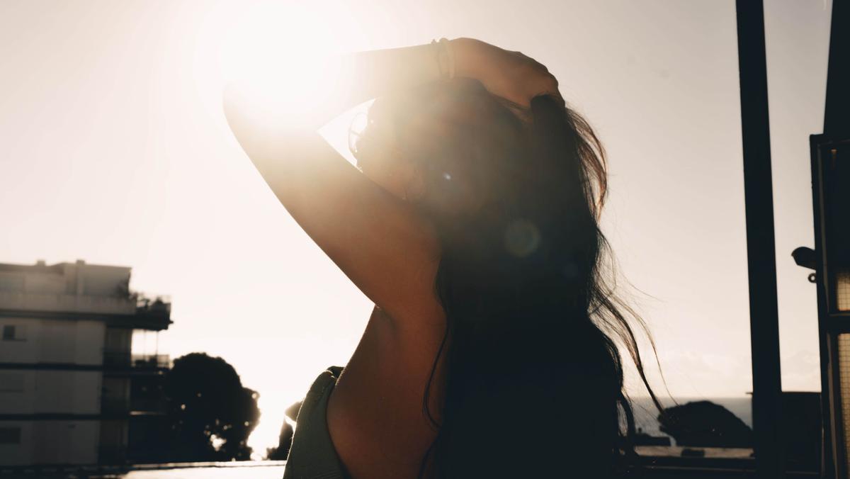 Detalle de la foto en la que una chica se sujeta el pelo mientras es acariciada por el sol. 