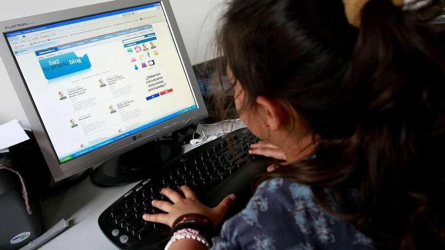 Una niña consulta internet en un ordenador.