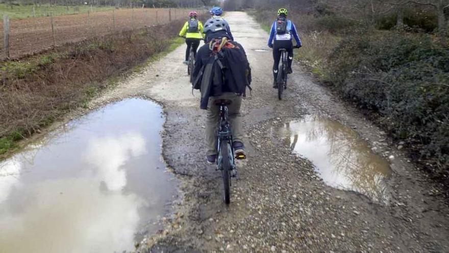 Un grupo de ciclistas recorre la carretea de Robledo a Linarejos, en pésimo estado.