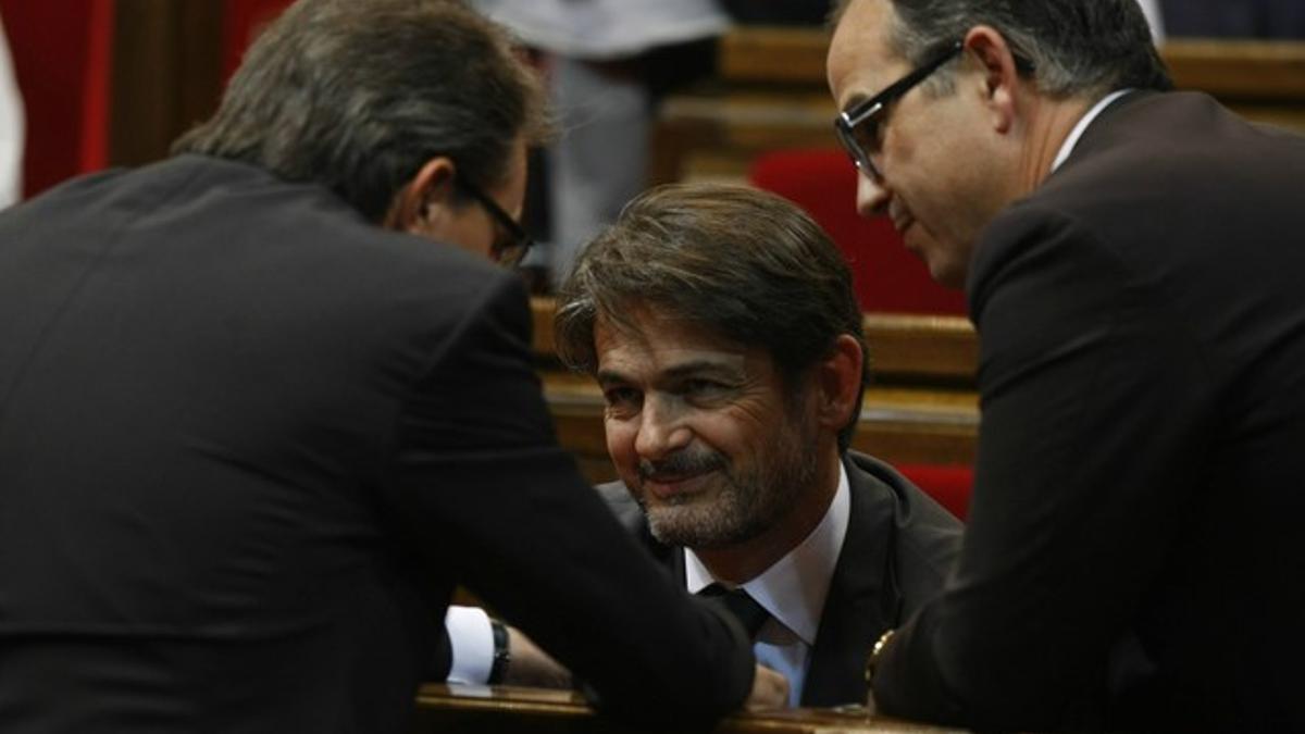 El portavoz de CiU, Oriol Pujol (centro) charla con el 'president' Artur Mas (de espaldas, izquierda) y Jordi Turull (derecha) en el Parlament, este miércoles.