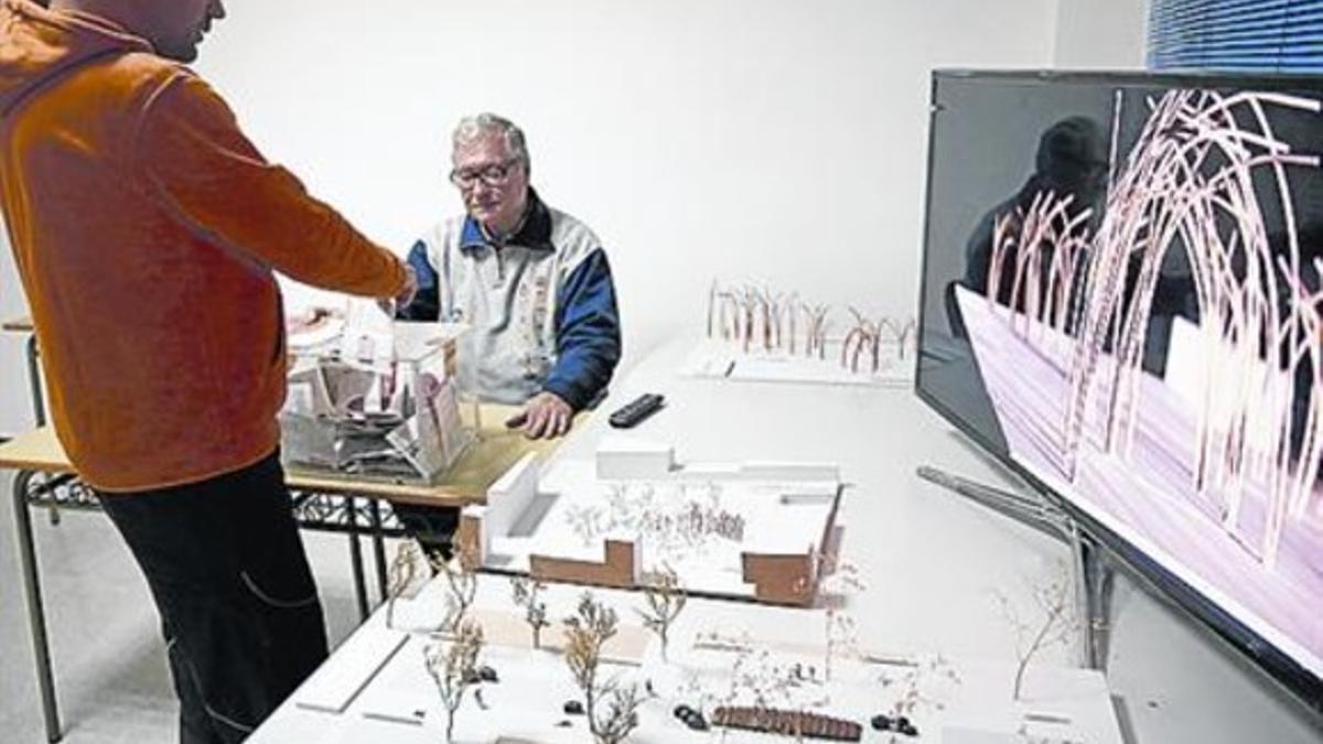 Un vecino vota su escultura favorita, junto a las dos maquetas.