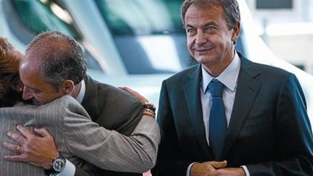 Francisco Camps y Rita Barberá se abrazan afectuosamente ante la mirada de José Luis Rodríguez Zapatero, ayer, en Valencia.