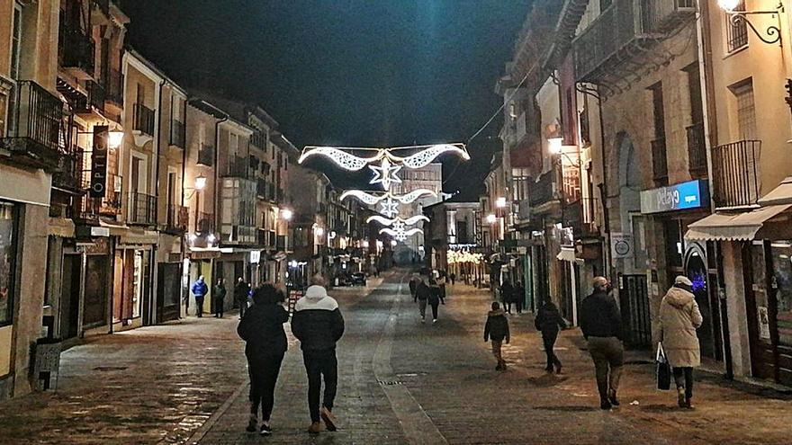 Vecinos pasean por la Puerta del Mercado, una de las calles adornadas con luces. | M. J. C.