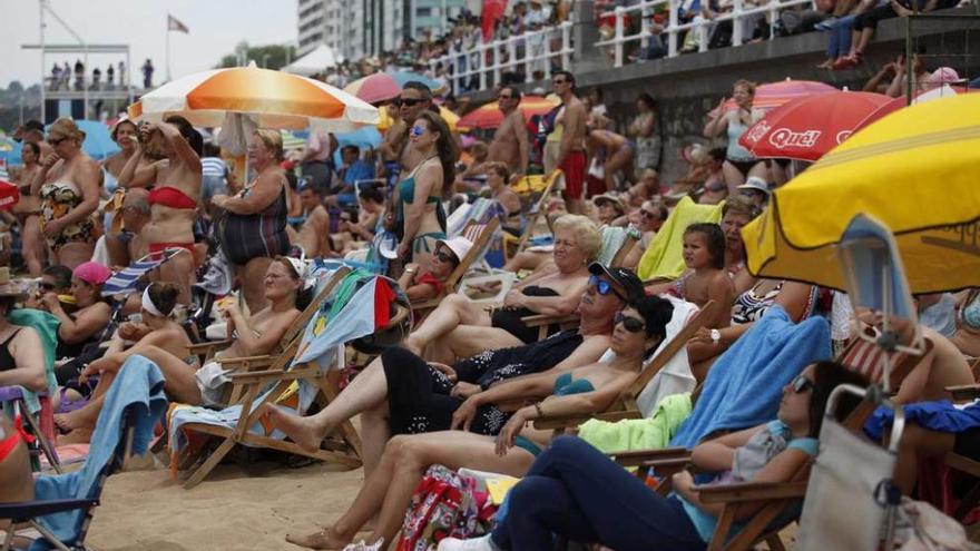 A la izquierda, público arremolinado en el Muro y asomados en las ventanas de los edificios. A la derecha, la Patrulla Águila en una de sus piruetas.