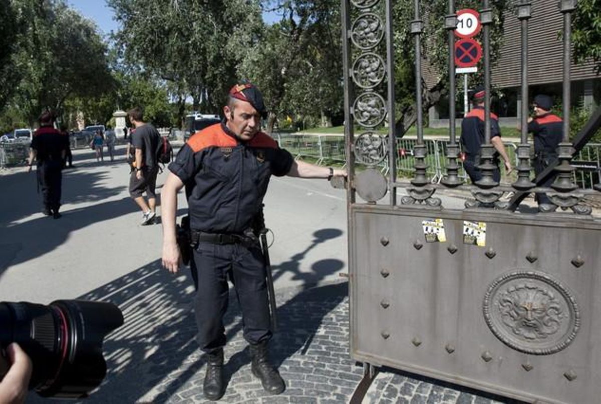 Un mosso d’esquadra col·loca cadenes a les portes del parc de la Ciutadella, on s’ubica el Parlament de Catalunya.