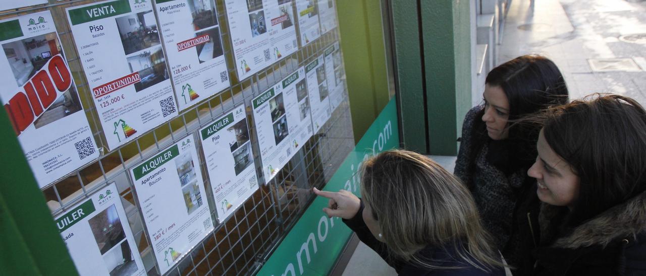 Jovenes ante el escaparate de una inmobiliaria.