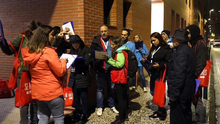 Varios voluntarios de Cáritas se reúnen en una intervención de la asociación junto a personas sin hogar.  | MIGUEL ÁNGEL GRACIA