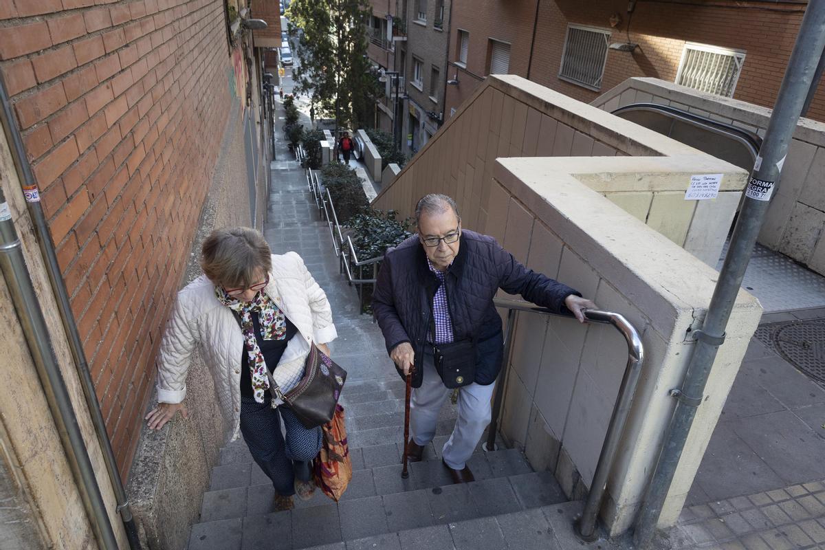 Una pareja sube los escalones junto a un tramo de escalera mecánica fuera de servicio en la Baixada de la Glòria, en el distrito de Gràcia.