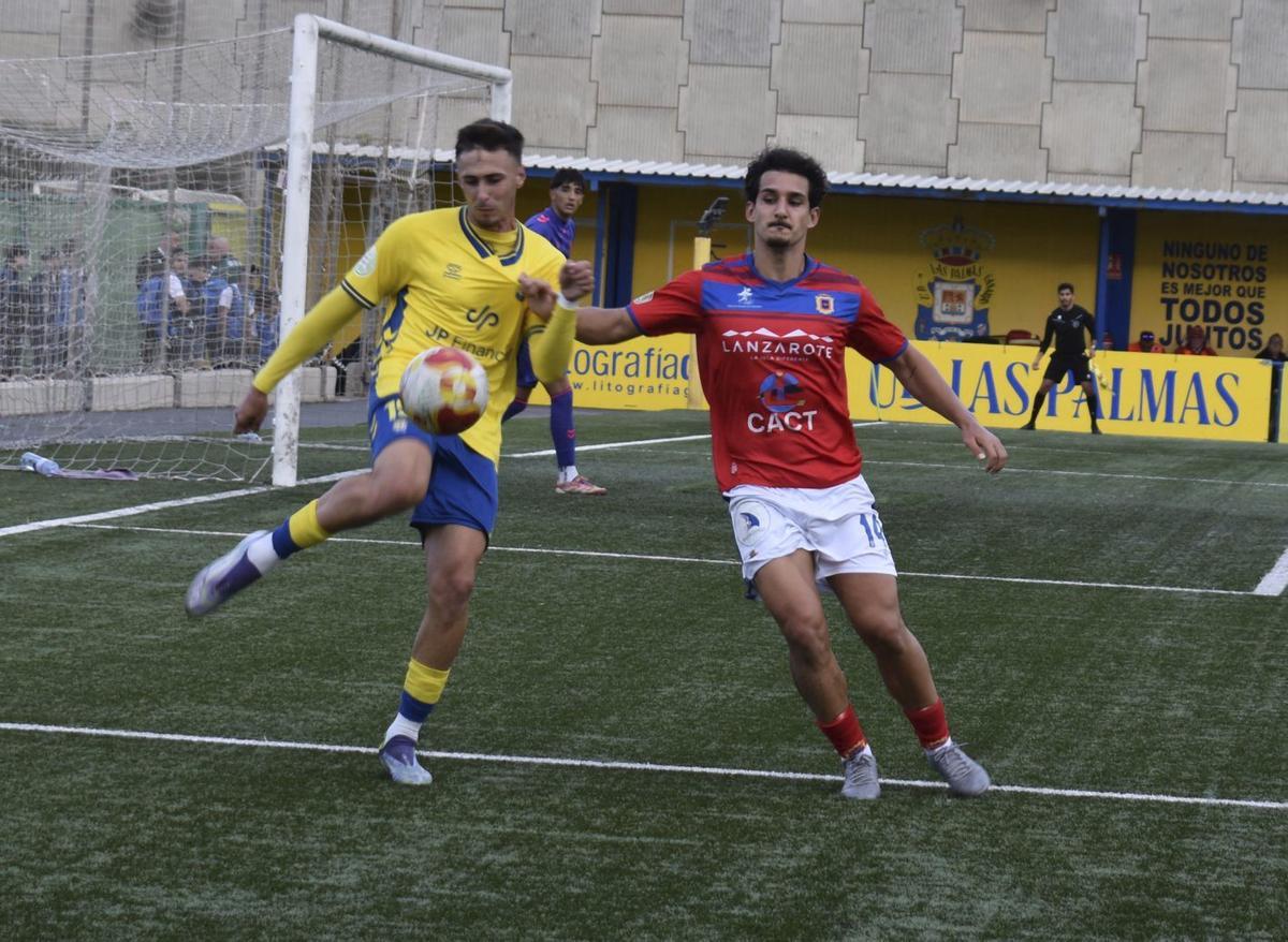 Adrián Rodríguez, de Las Palmas C, despeja el balón ante la presencia de Pablo, del Lanzarote