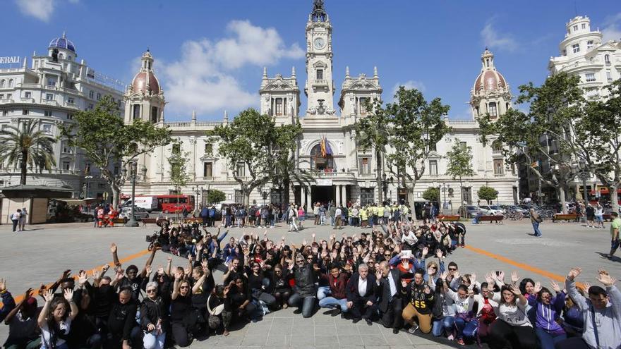 Voluntarios vestidos de negro forman una equis en la plaza del Ayuntamiento de València.