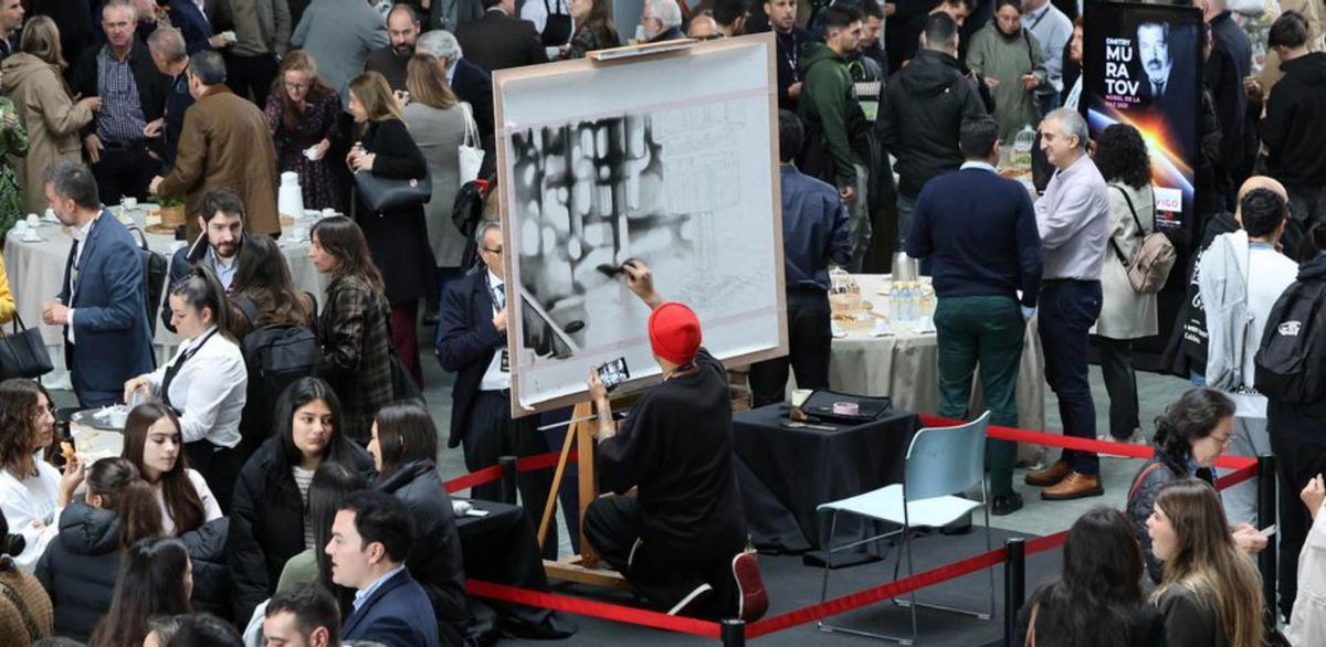 Marcos Míguez Puhinger impregnó el «hall» de arte 
Marcos Míguez Puhinger, artista local multidisciplinar, aportó un toque de creatividad en el hall del auditorio Mar de Vigo. El miércoles, con motivo de la visita del Nobel de la Paz de 2021, hizo un cuadro del Puente de Rande a modo de «metáfora». Ayer, plasmó una cadena de montaje de chips fotónicos, industria que marcará el futuro de la ciudad y el área.