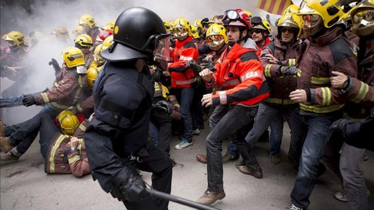 Mossos y bomberos enfrentados ante el Parlament.