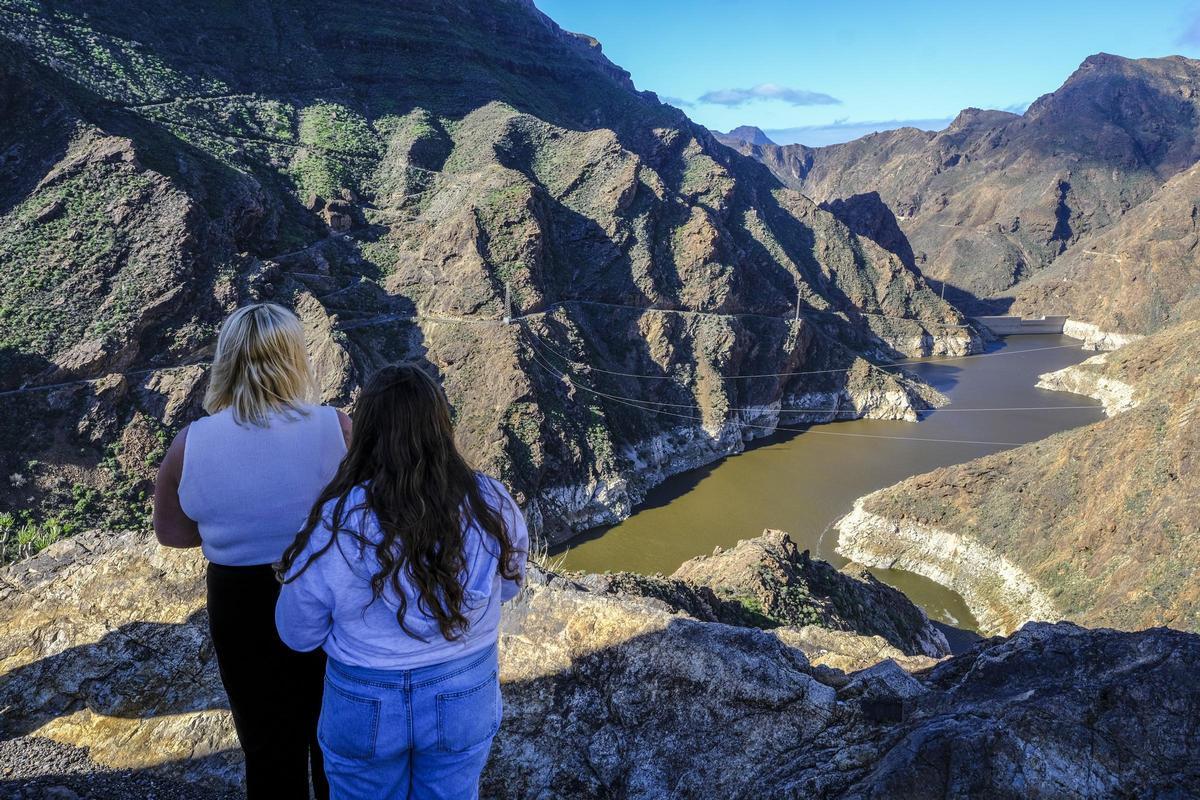 Dos personas miran la presa de El Parralillo, donde las últimas lluvias han aumentado su nivel de agua más de 14 metros.