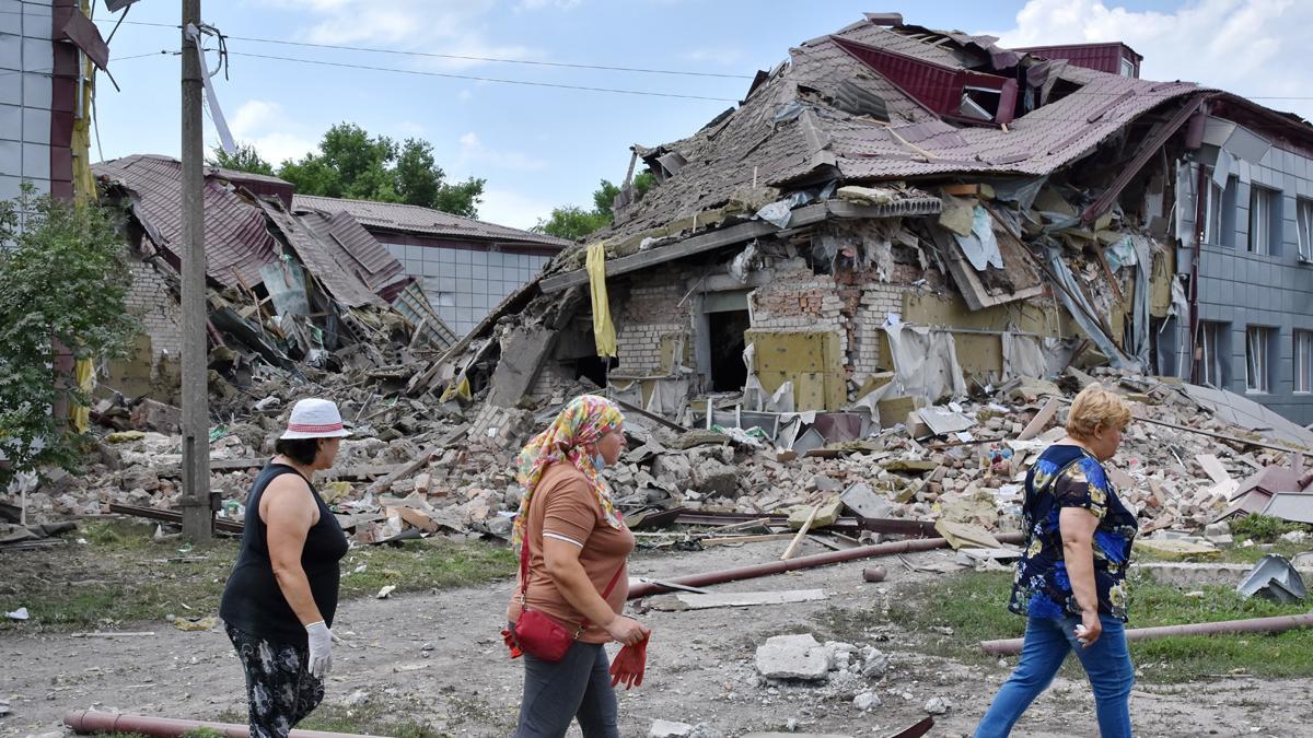 Residentes de Komyshuvakha, en Ucrania, pasan junto a una escuela secundaria dañada en un ataque