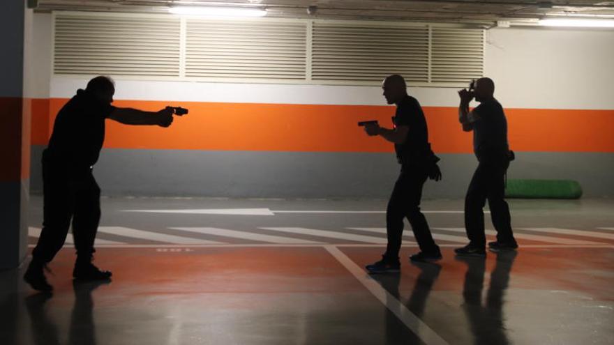 Tres agentes de la Policía Local de San Vicente del Raspeig simulan el uso de un arma Taser en el interior de un aparcamiento.