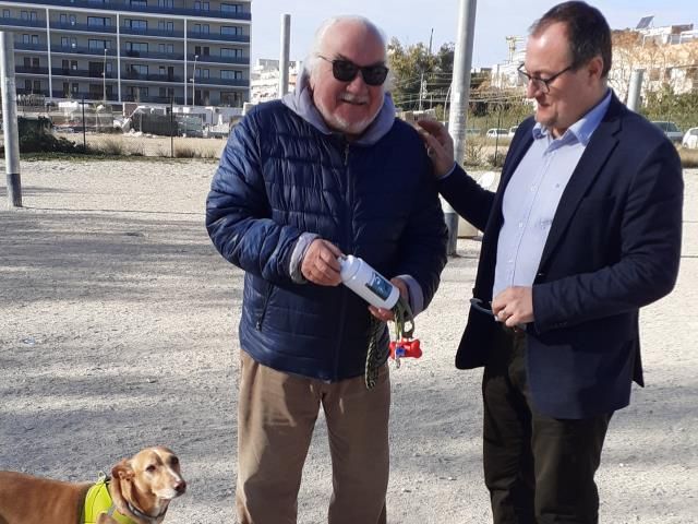 El alcalde de Vilanova, Juan Luis Ruiz, entrega una botella de agua al propietario de un perro, en el marco de la campaña 'No deixis rastre'