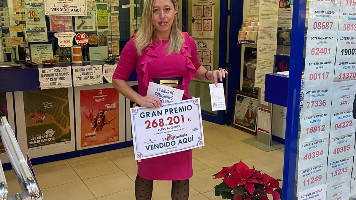La lotera, Patricia Yagüe, sostiene el cartel con el premio y el boleto ganador.