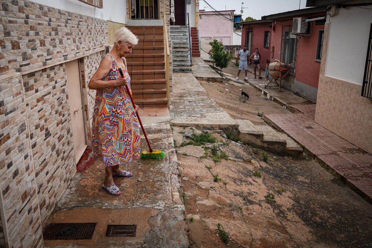 Una vecina barre en la puerta de su casa, donde accede con dificultad, en Las 800.