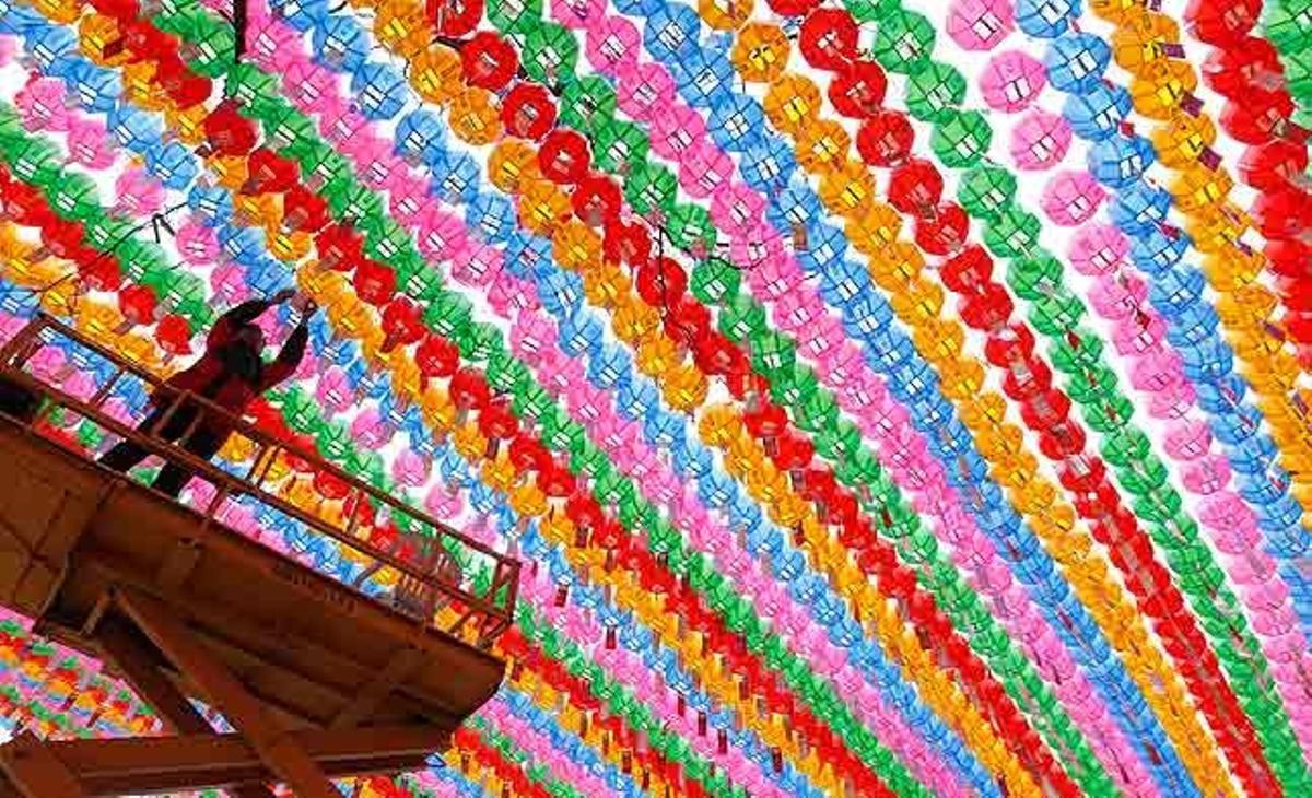 Un operari col·loca pregàries, amb noms escrits en targetes, en llanternes amb forma de flor de lotus com a part de la preparació per a l’aniversari de naixement del Senyor Buda, al temple Jogye, a Seül (Corea del Sud),