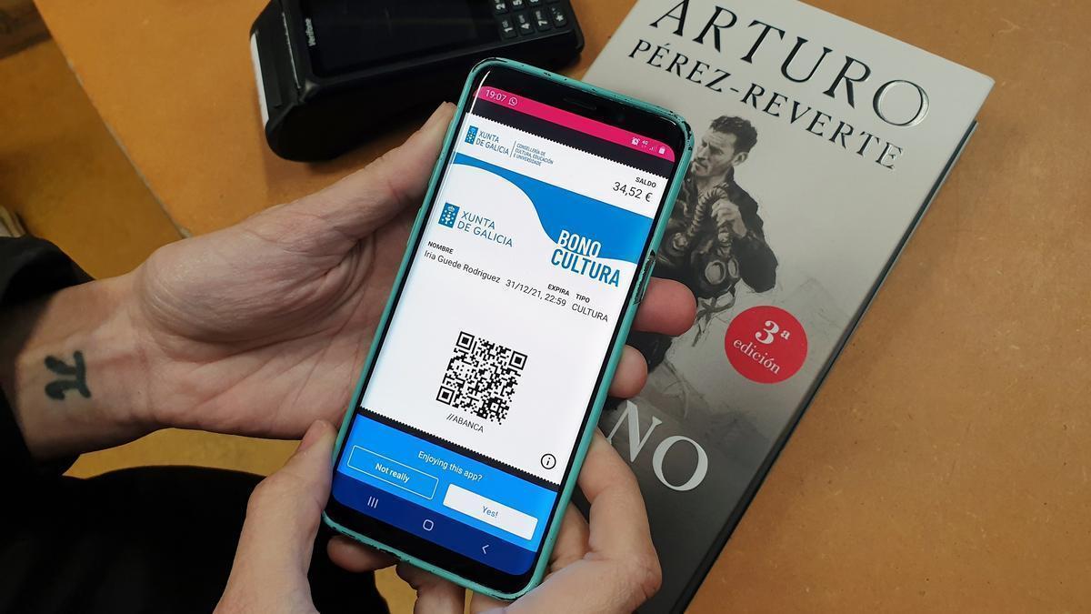 Un cliente de un librería enseña el código del bono, el año pasado