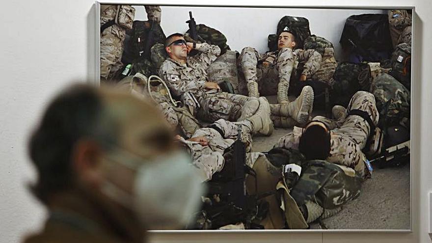 A la izquierda, una foto de soldados descansando. A la derecha, uno de los uniformes expuestos y detrás, Barbón y Canteli, de espaldas, viendo una de las fotos. | Luisma Murias