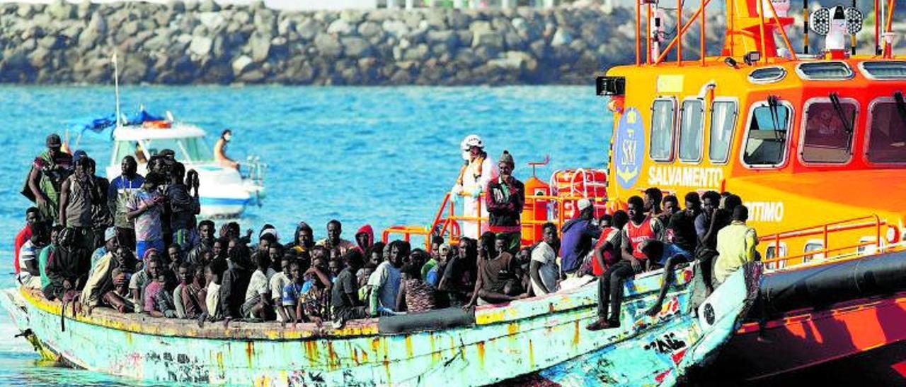 Los pasajeros de un abarrotado cayuco  llegan al puerto de Arguineguín tras ser auxialidos por Salvamento Marítimo.