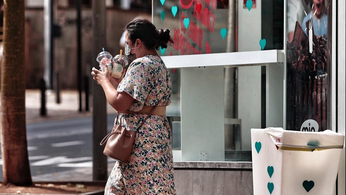 Una mujer con mascarilla combate el calor con dos batidos helados.