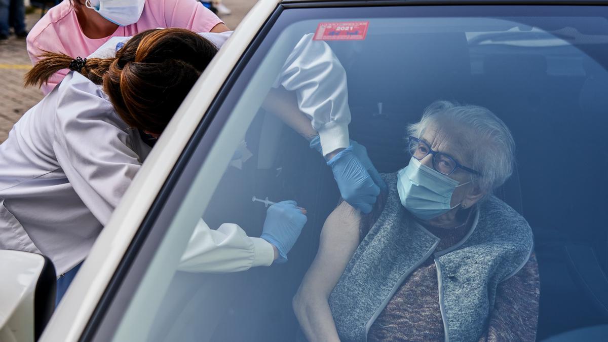 Una mujer de más de 80 años recibe una vacuna dentro de un coche en Vitoria.