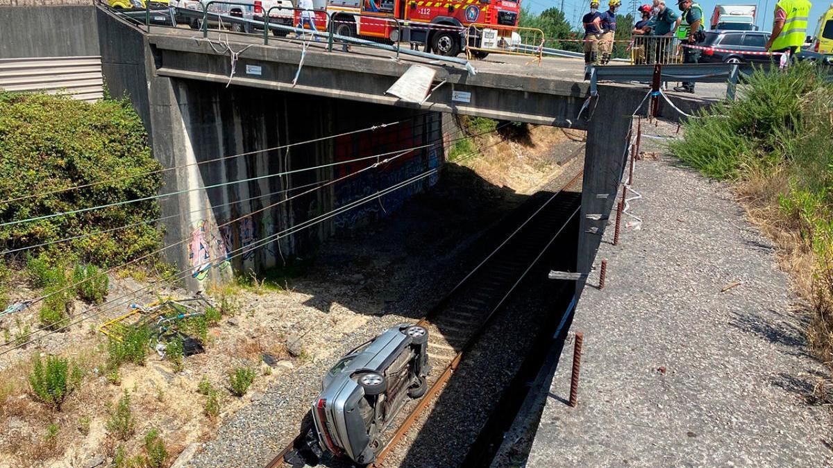 El coche, volcado, en la vía del tren que cruza As Gándaras