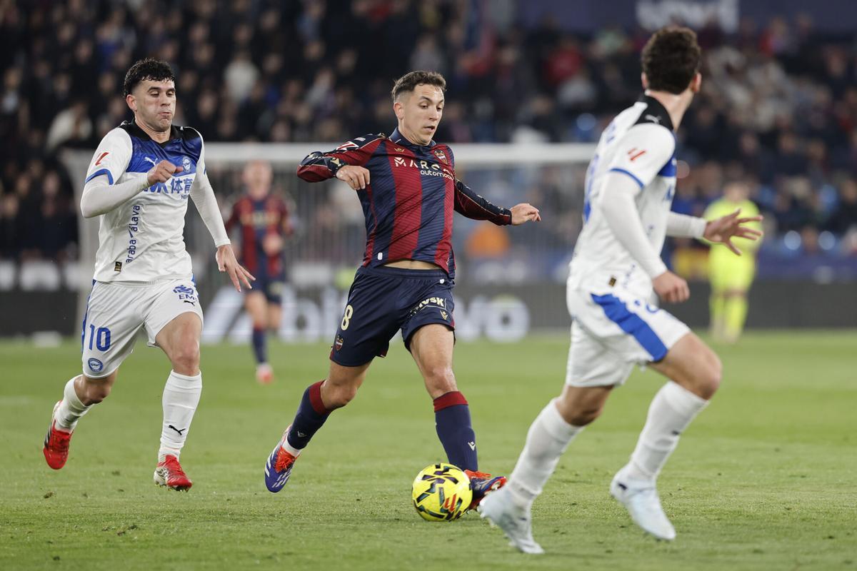 El centrocampista del Levante Jon Ander Olasagasti (c) se escapa de Carles Aleñá (i), del Alavés, durante el partido de la jornada 26 de LaLiga de fútbol que Levante UD y Deportivo Alavés disputaron este viernes en el estadio Ciutat de Valencia. EFE/Ana Escobar. (Levante) (Alavés) Sustituye texto y agrega foto