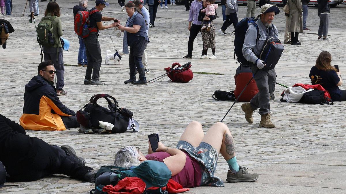 Turistas y peregrinos tumbados en la plaza del Obradoiro de Santiago.