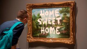 Un visitante contempla el cuadro de Banksy, ’Home sweet home’.