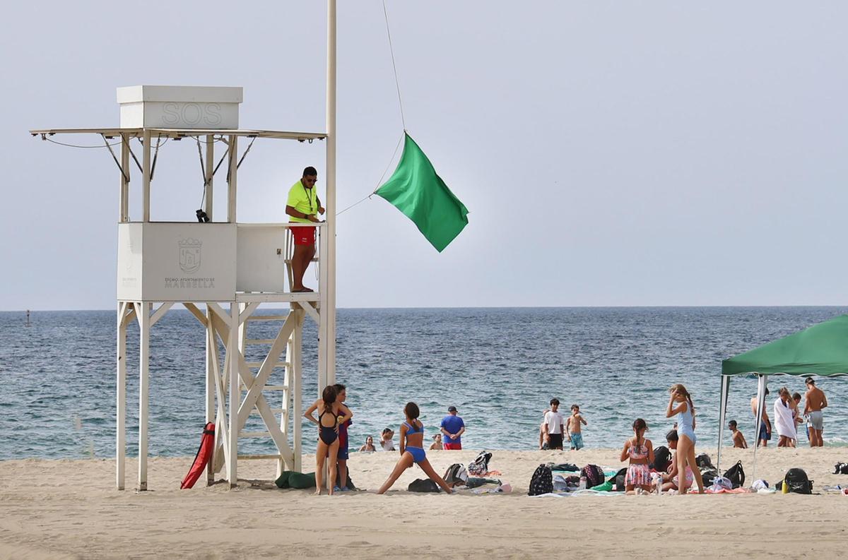 Un socorrista iza la bandera verde en una de las playas de Marbella durante el pasado verano.