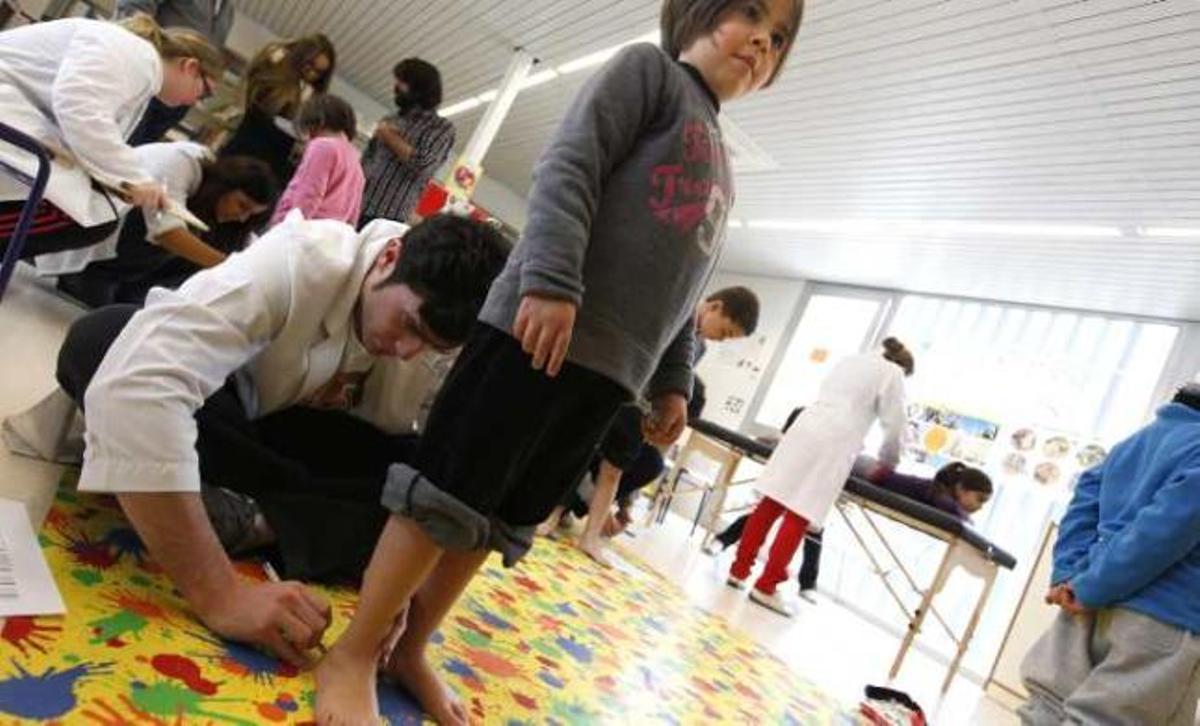 Los alumnos de Podología de la UMH examinando los pies de niños en El Fabraquer.