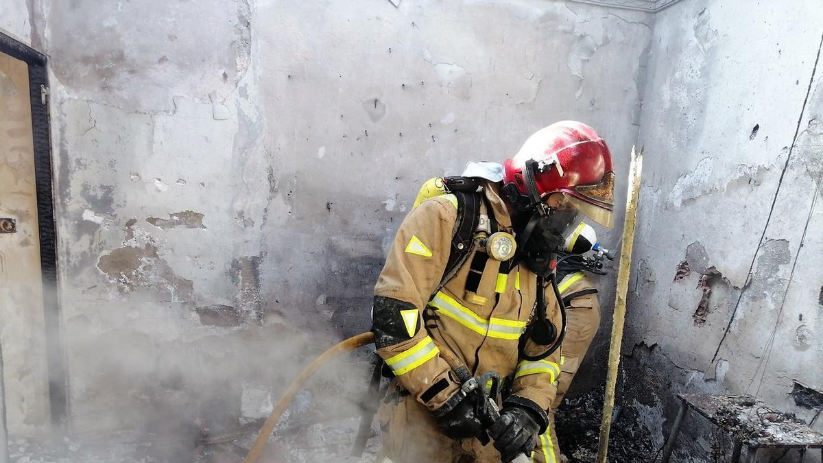 Un bombero trabaja en la vivienda incendiada.