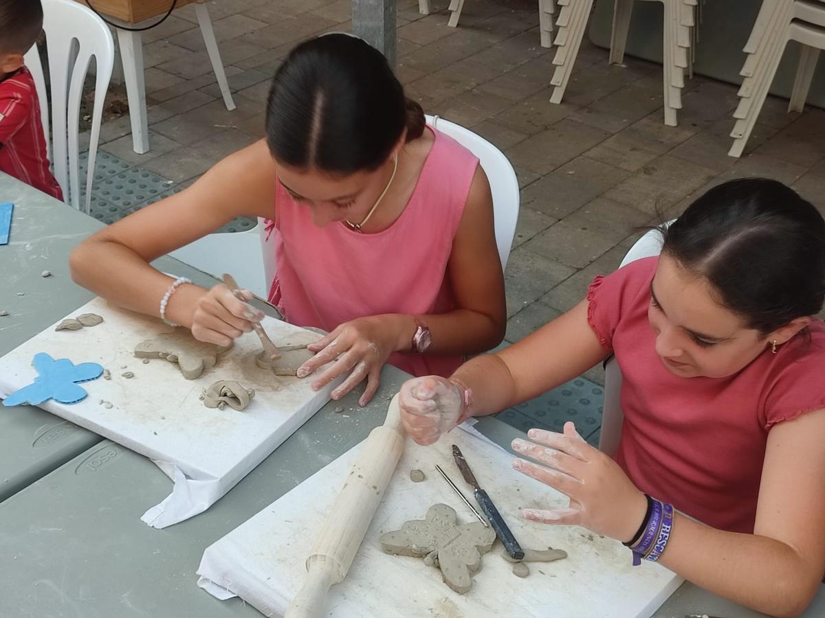 Dos niñas participan en un taller de elaboración de piezas de barro y arcilla.
